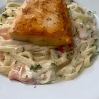 Salmon Milano · Salmon served on a bed of fettuccine tossed with tomatoes in a white wine cream sauce.