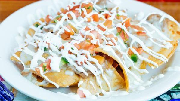 Nachos Grande · Home-made crispy corn tortilla chips pilled with beans and melted cheese, topped with sour cream, pico de gallo, and guacamole.