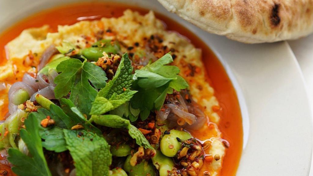 Gf Chickpea & Fava Plate · Chickpea puree topped with warm caramelized red onions, green favas, aleppo chili oil, dukkah, and herb salad. Served with gluten-free bread.. Contains: Dairy, Egg, Sesame, Tree Nut (Hazelnut)