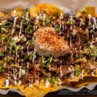 Nasty Nachos · Tortilla chips drenched with savory birria meat, queso, corn, salsa, onions, and jalapeño.