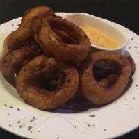 Onion Rings · A basket of thick cut beer battered onion rings with texas petal sauce.