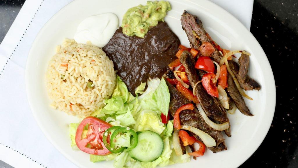 Bistec Encebollado · Grilled steak and sautéed veggies. Served with rice, beans, tomatoes green pepper, and two floured tortillas.