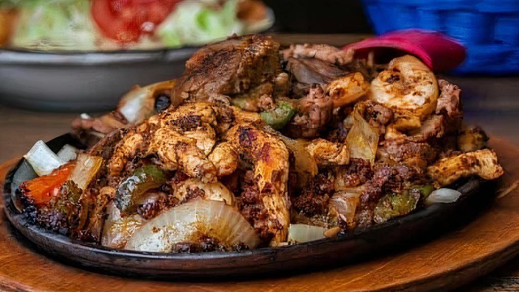 Parrillada Mexicana · Carnitas (pork), chorizo (Mexican sausage), shrimp, chicken and steak, all seasoned and grilled with bell peppers, onions, and tomatoes on a sizzling hot plate. Served with Spanish rice, refried beans, a salad, and flour tortillas.
