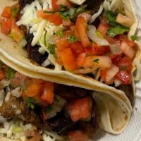 2 Grilled Steak Tacos  · A soft shell tortilla filled with grilled steak topped with shredded cheese and salsa with h...