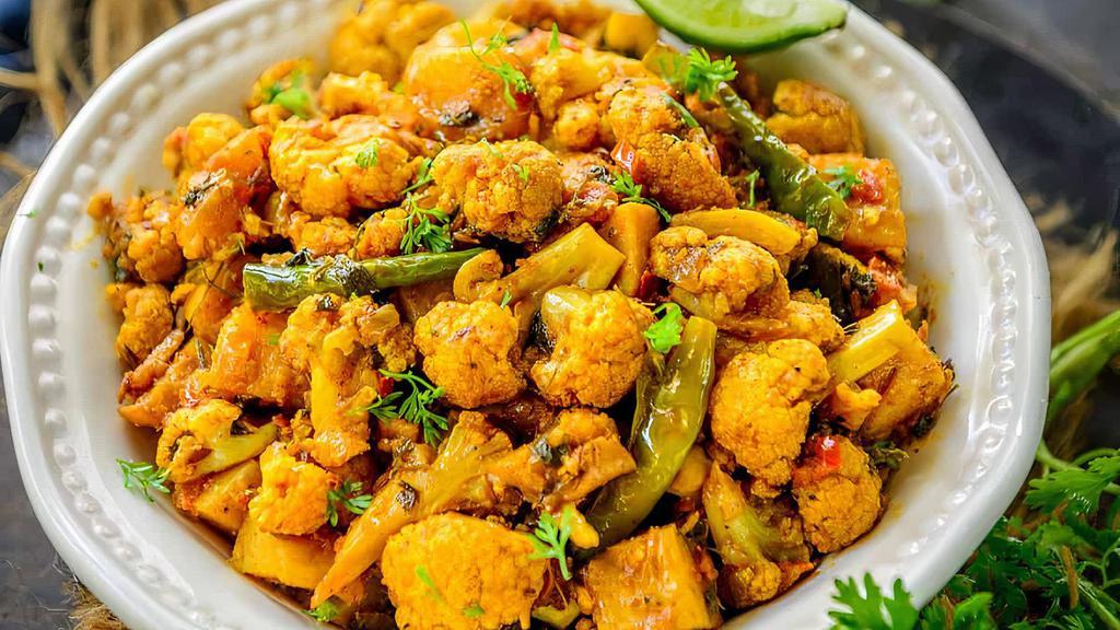 Aloo Gobi (V) · Vegan, gluten free. Steamed cauliflower with potatoes and tomatoes, flavored with Indian herbs and spices.