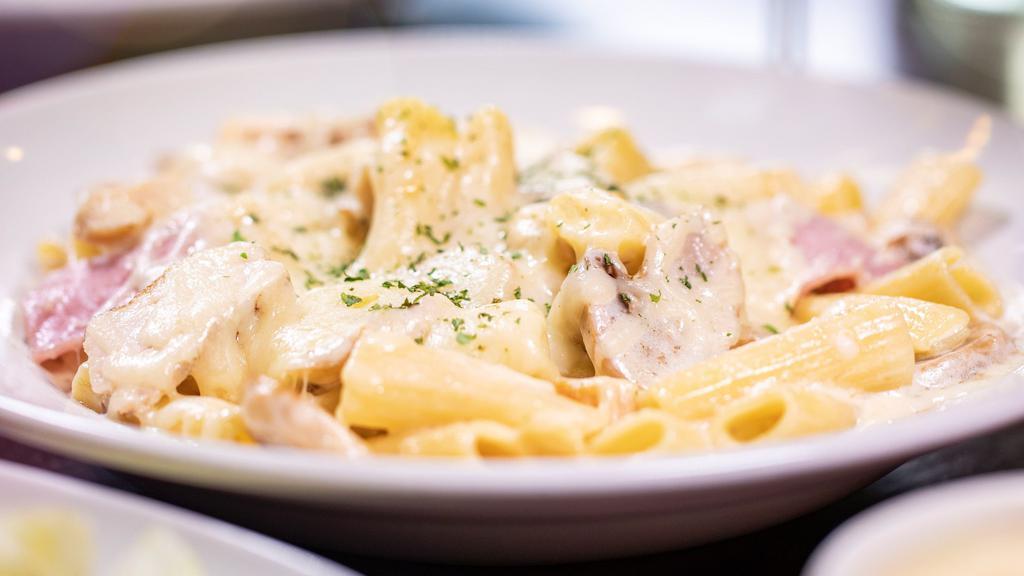 Pollo Affumicato · A juicy sliced grilled chicken breast sautéed with ham and mushrooms and tossed with ziti and mozzarella cheese in our signature Alfredo sauce.