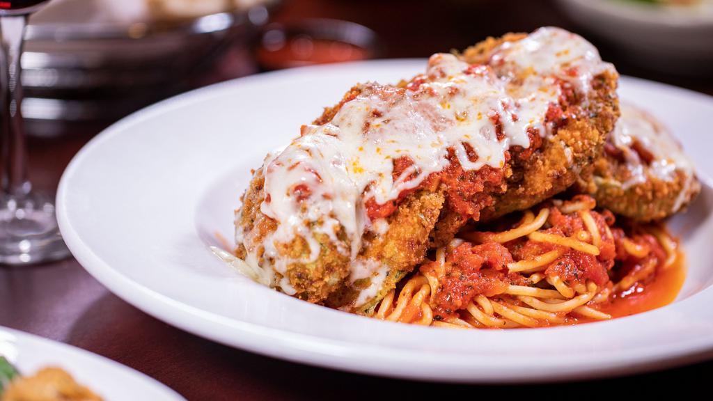 Eggplant Parmesan · Fresh slices of lightly breaded eggplant topped with marinara herb sauce and melted mozzarella. Served over spaghetti and sprinkled with Parmesan cheese.