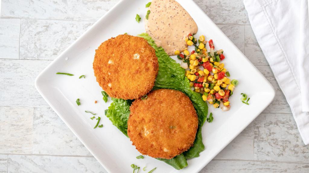 Crab Cakes · Hand formed crab cakes (2) made of crab meat and a super blend of vegetables, seasoning and a select of spices battered and lightly coated with bread crumbs. Served with our home-made remoulade sauce and corn salad.