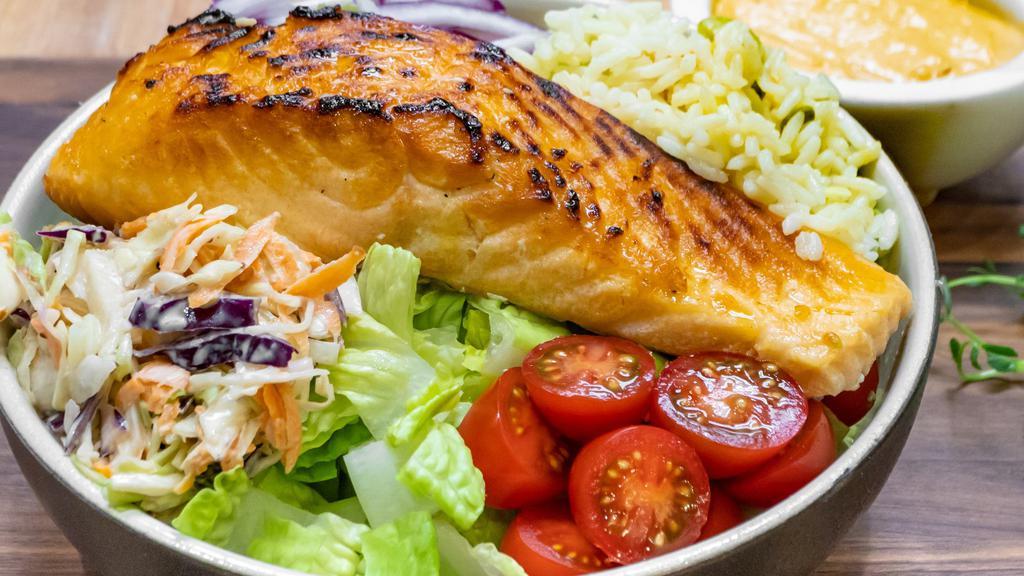 Salmon Bowl · Seared salmon laid on a bed of greens, coleslaw, rice, tomato, and corn salsa.