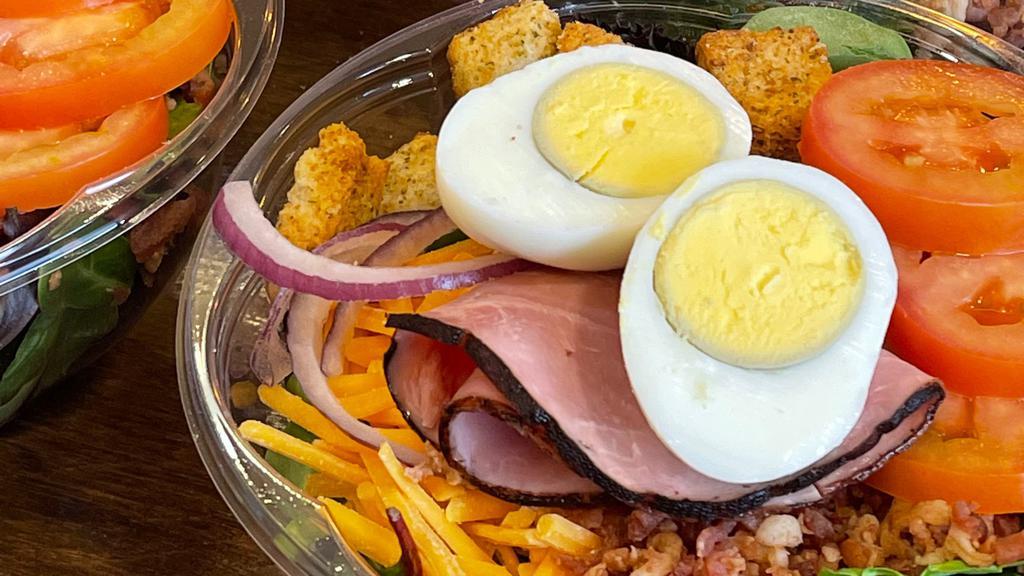 Cobb Salad · Proteins like bacon, ham, and boiled eggs. Mixed with tomato, red onions, cheddar cheese, and croutons.