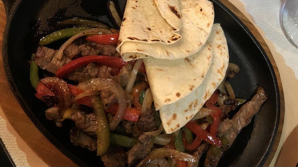 Grilled Steak Fajitas · Grilled steak, sautéed onions, jalapeños, red and green pepper served with flour tortillas, pico De gallo, sour cream and guacamole. Served with Mexican rice.