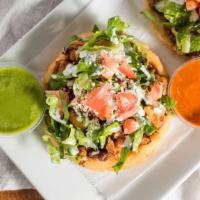 Sope · Handmade thick corn tortilla, topped with beans, lettuce, tomato, sour cream, and cotija che...