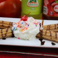 Churros · Two churros served with chocolate sauce, whipped cream and sprinkles.