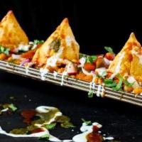 Samosa Chaat · Samosa topped with chickpea curry, onions, mint and tamarind  chutney.