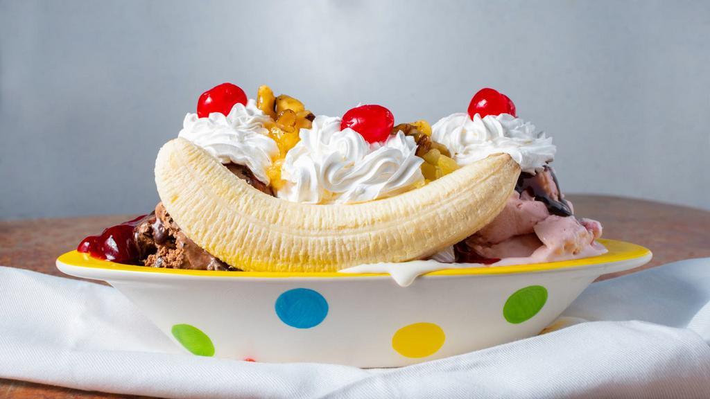 Banana Split (Hand Dipped) · Chocolate syrup, crushed pineapple, strawberry topping over three scoops of hand dipped ice cream, stuffed between two banana halves, piled with wet walnuts, whipped cream and cherries.