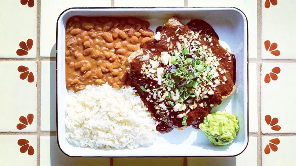 Chicken Enchiladas · House rolled heirloom tortillas stuffed with local farm chicken stewed with tomatoes, chipotle, onions, and spices and served with rice, pinto beans, guacamole and topped with queso fresco & choice of salsa (GF/ pictured w/mole sauce)