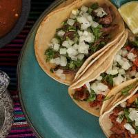 Tacos · Traditional style tacos topped with onions and cilantro with the tortilla of your choice cor...