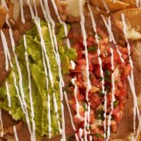 Nachos Supreme · Corn tortillas chips topped with beans, melted cheese, guacamole, pico de gallo and sour cre...
