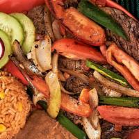 Bistec A La Mexicana · Ribeye braised steak topped with tomatoes, jalapenos peppers and onions, served with rice, b...