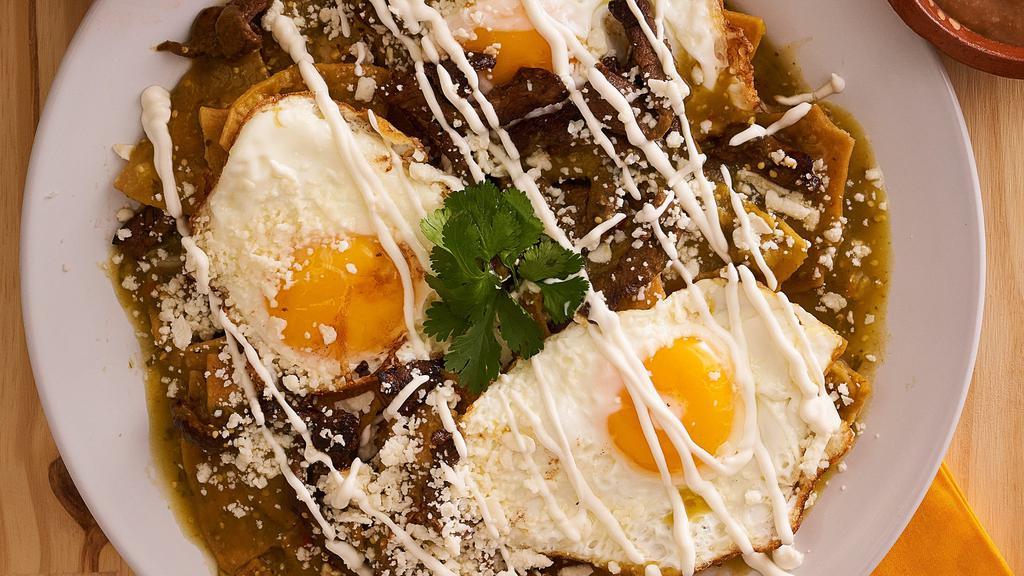 Chilaquiles · Corn tortilla chips simmered with the sauce of your choice (tomatillo/guajillo/chipotle) topped with fresh cheese, sour cream and onions. served with side of beans.