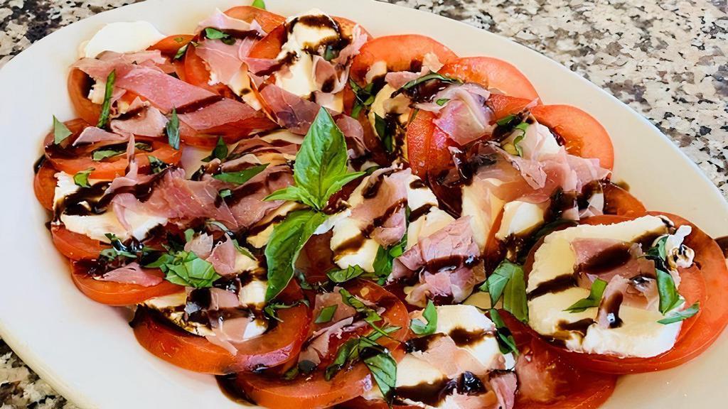 Capri Salad · Tomatoes, fresh mozzarella, prosciutto and basil with a drizzle of balsamic glaze .