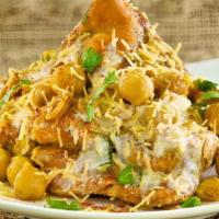 Samosa Chaat · Samosa topped with chickpea curry, onions, mint, and garlic chutney.