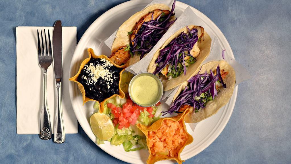 Fish Tacos · Three soft corn tortillas with marinated, grilled Tilapia fish served with shredded cabbage, cheese, cilantro and onions in a white sauce.