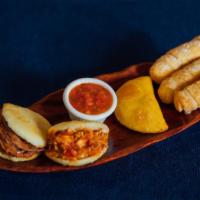 Sazon Plato Surtidos · A sampler platter containing two arepitas, one beef, one chicken, and one empanadita with  b...
