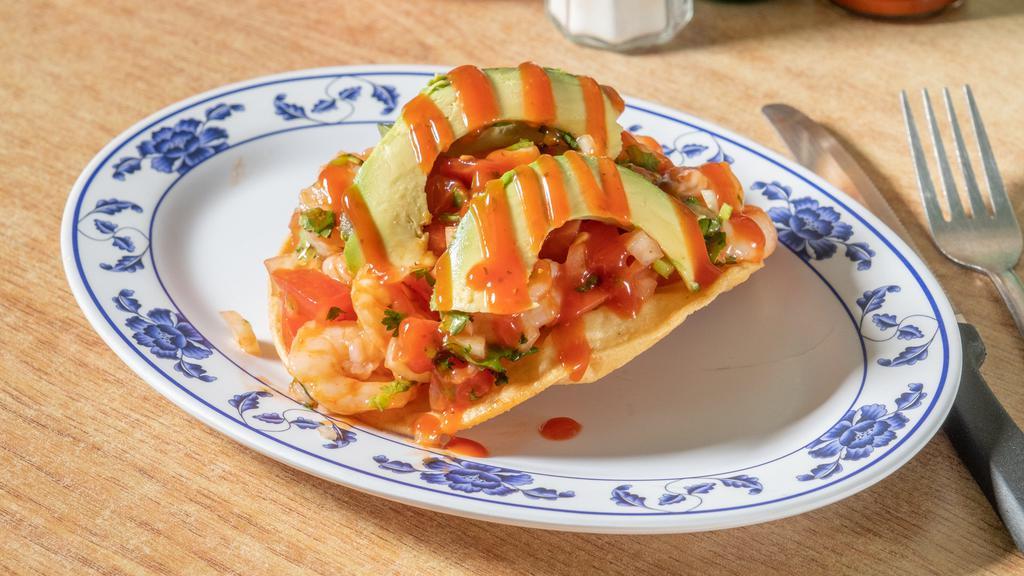 Shrimp Tostada · Flat fried tortilla topped with shrimp mixed with tomatoes, onions, cilantro and a sauce on top and avocado.