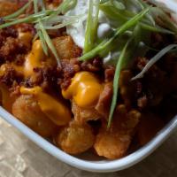 Messy Tots · Crispy Tater Tots topped with Cheddar Cheese Sauce, Bacon, Sour Cream & Green Onions