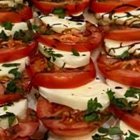 Caprese · Fresh layered mozzarella, tomato, drizzled with balsamic reduction over arugula and basil in...