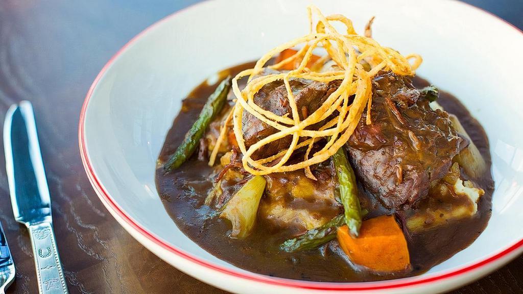 Yankee Pot Roast · Tender beef slow-braised in a whiskey gravy with root vegetables and green beans. Served over mashed potatoes and topped with crispy onions.
