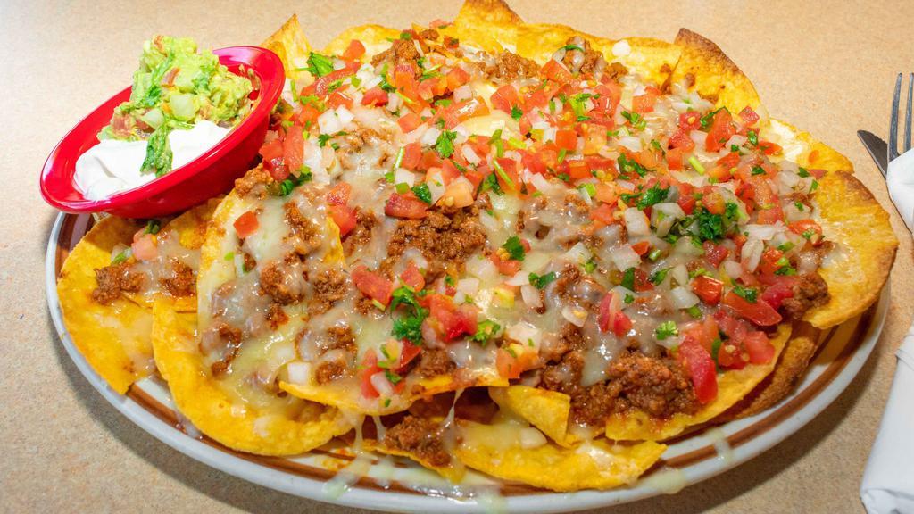 Nachos Fiesta · Choice of shredded chicken, ground beef, or pork, topped with melted Cheddar cheese, refried beans, pico de gallo, sour cream, and guacamole.