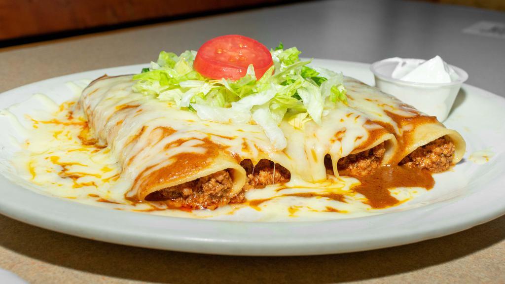 Fiesta Enchiladas · Four enchiladas, one of each: ground beef, shredded chicken, white Cheddar cheese, and refried beans. Topped with enchilada sauce, lettuce, tomatoes, and sour cream (enchilada sauce contains traces of peanuts).