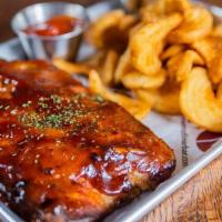 1/2 Rack Baby Back Ribs · Slow roasted half rack of baby back ribs, hickory smoked BBQ sauce, served with beer battere...