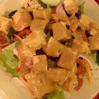 Sautéed Tofu · Crispy golden brown deep-fried tofu topped with peanut sauce on a bed of green salad.