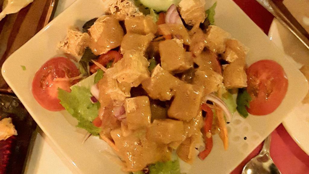 Sautéed Tofu · Crispy golden brown deep-fried tofu topped with peanut sauce on a bed of green salad.