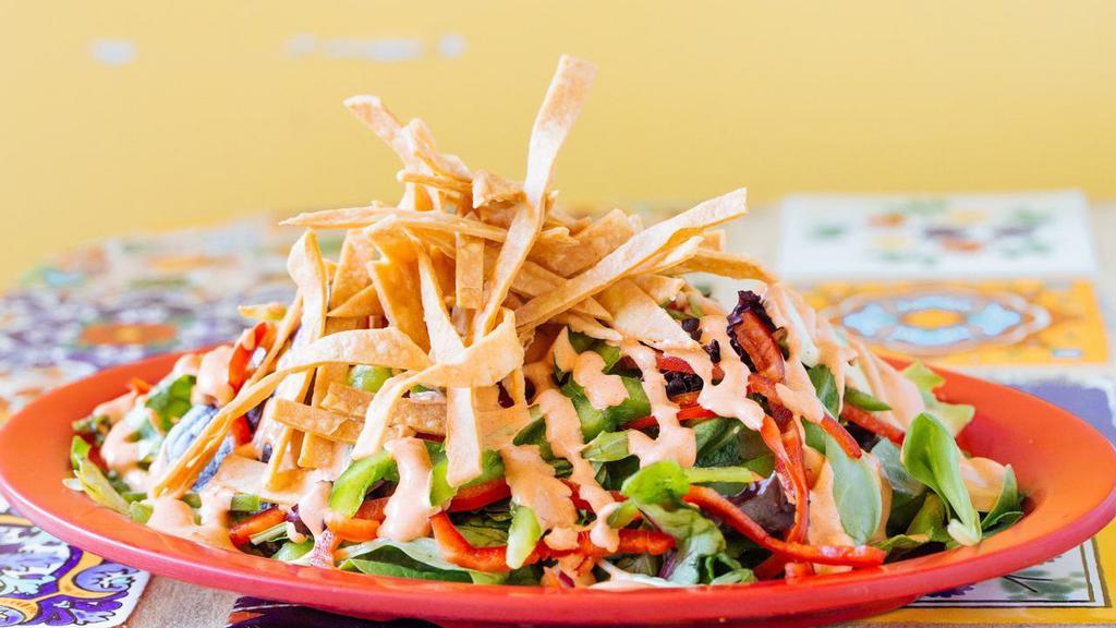 Ensalada De Tortilla · A combination of spring mix, romaine lettuce, corn tortilla strips, sweet peppers, avocado and our delicious chipotle, dressing.
