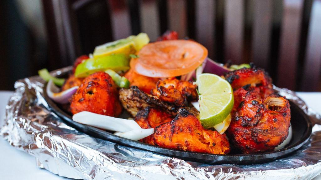 Tandoori Chicken · Chicken leg quarters marinated in yogurt, fresh spices and lemon juice then barbecued in the clay oven.