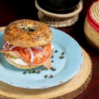Lox Bagel · Smoked salmon on bagel with cream cheese, garnished with tomato, onions, cucumbers, and cape...