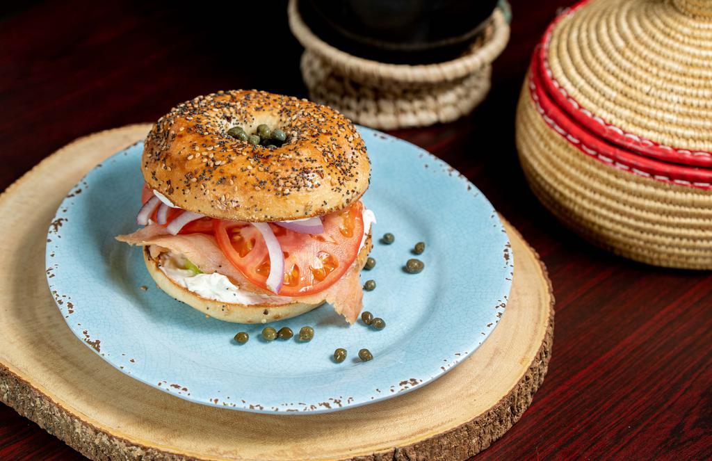 Lox Bagel · Smoked salmon on bagel with cream cheese, garnished with tomato, onions, cucumbers, and capers.