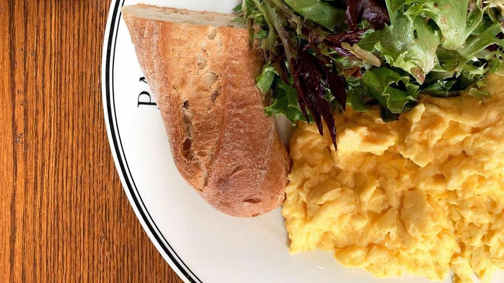 Scrambled Eggs · Eggs scrambled, served with a side of fresh greens, and baguette slice.
