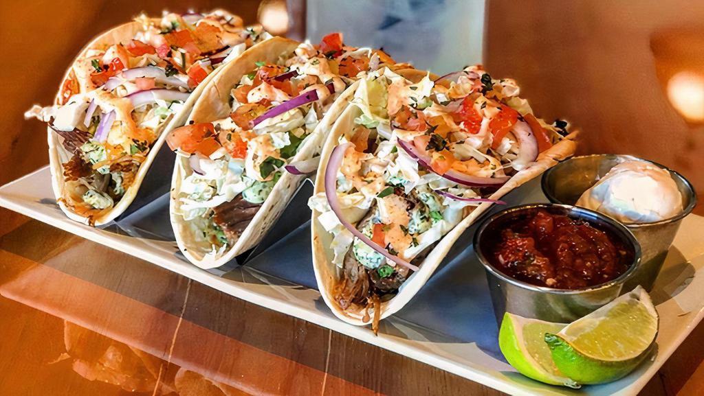 Pulled Pork Tacos · Three huge pulled pork tacos with Napa cabbage slaw, tomato, house salsa and guacamole, sour cream, chipolte mayo and cilantro aioli.
