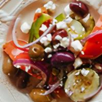 Horiatiki · A traditional village salad made with vine ripen tomatoes, cucumber, sliced onion, feta chee...