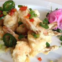 Rock Shrimp Tempura · Shrimp tempura on top of a mixed green salad with sauce.