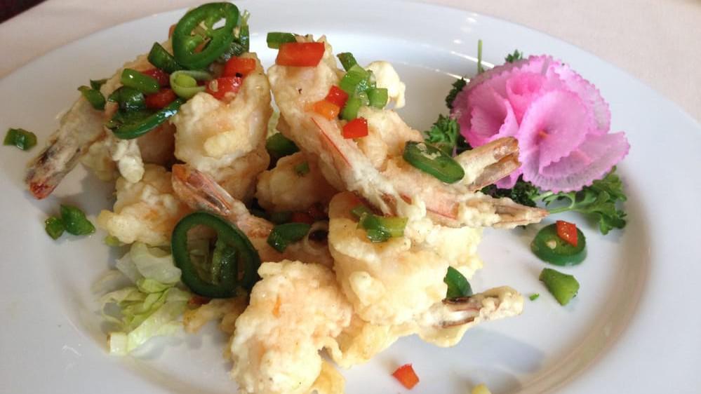 Rock Shrimp Tempura · Shrimp tempura on top of a mixed green salad with sauce.