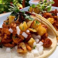Tacos Al Pastor · Two pork tacos, cooked in a traditional adobada sauce, with diced pineapple and white onion ...
