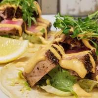 Tuna Tacos · Togarashi tuna pan-seared served over a bed of lettuce, radish, cucumber, and white onions, ...