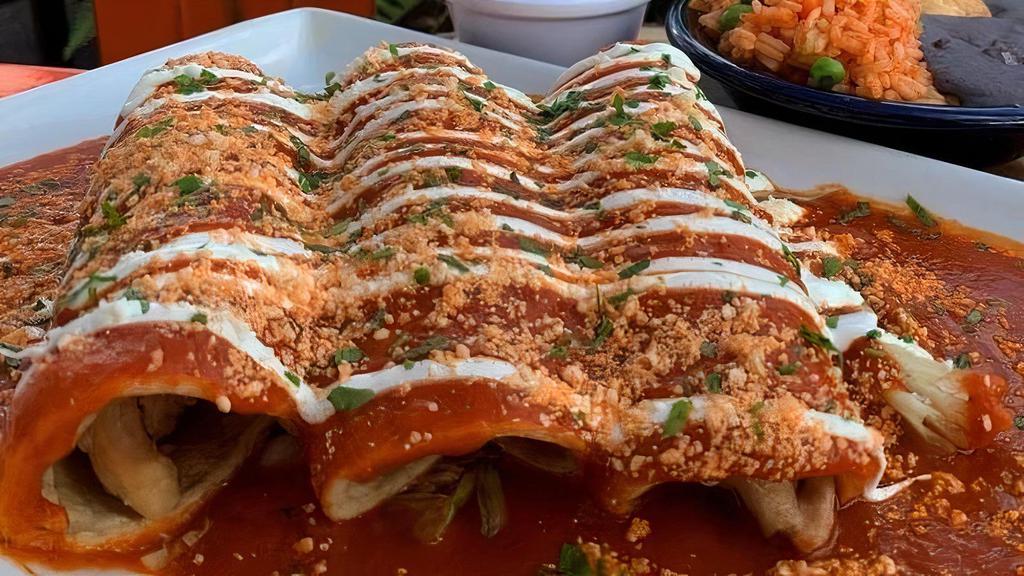 Pollo Enchiladas · Three corn tortillas filled with pulled chicken and cheddar cheese topped with guajillo salsa, sour cream, cotija cheese, and small sides of rice, beans, and guacamole