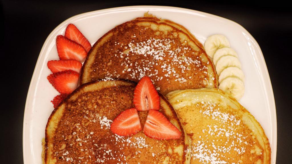 Homemade Buttermilk Pancakes · Three fluffy homemade pancakes that are topped with a sprinkle of powdered sugar.